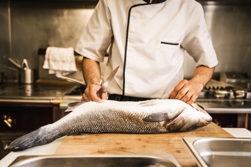 Enzo, chef du restaurant Le Lien, prépare un poisson